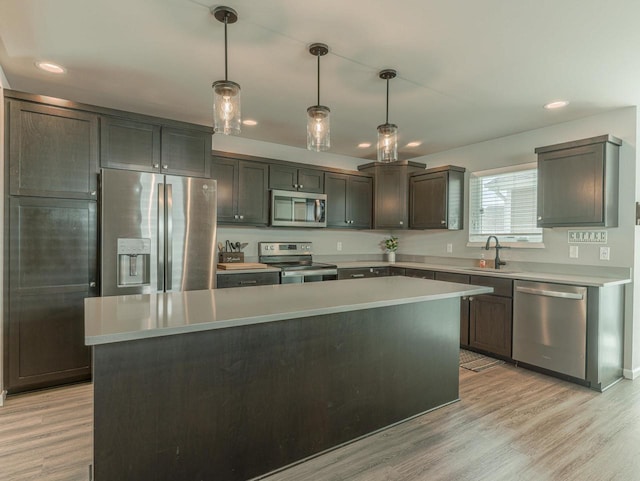 kitchen with light wood-type flooring, light countertops, a kitchen island, and stainless steel appliances
