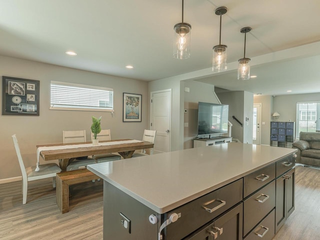 kitchen featuring a kitchen island, decorative light fixtures, light wood finished floors, and light countertops