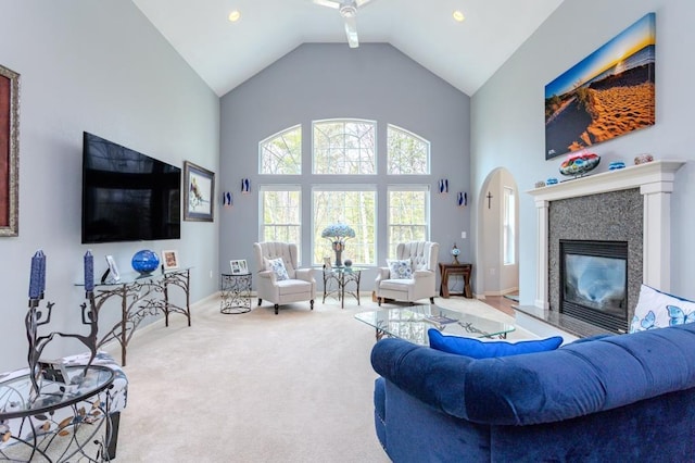 living room featuring carpet flooring, a glass covered fireplace, and high vaulted ceiling