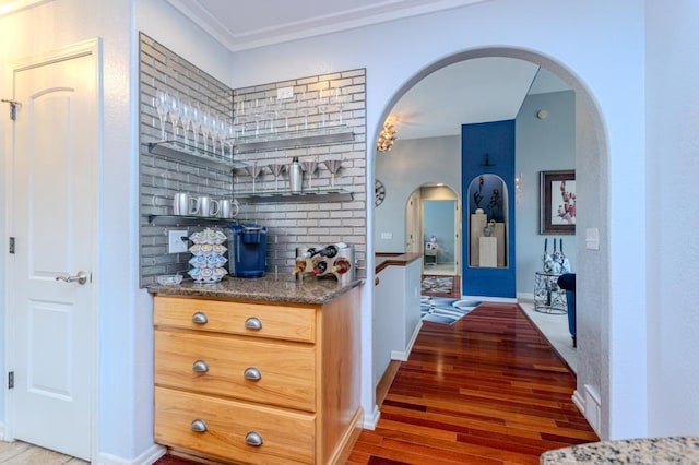bar with crown molding, arched walkways, baseboards, and light wood-style flooring