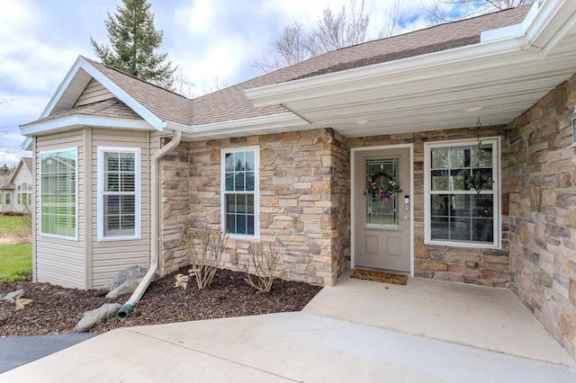 property entrance with a shingled roof and stone siding
