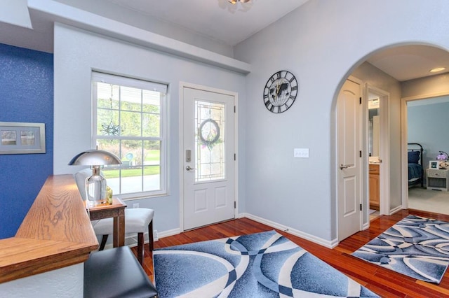 entryway featuring baseboards, arched walkways, and wood finished floors