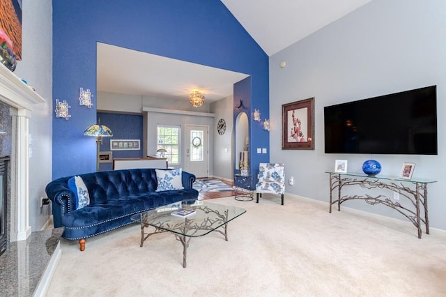 living area with high vaulted ceiling, baseboards, carpet flooring, and arched walkways