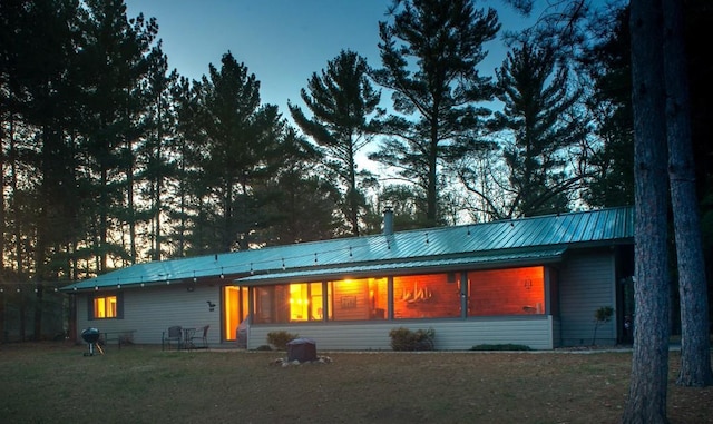 back of house with a lawn and metal roof