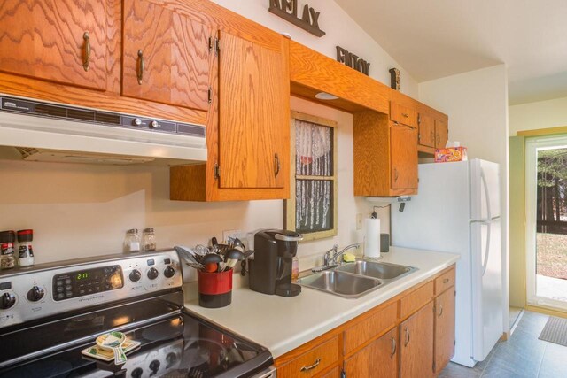 kitchen with freestanding refrigerator, electric range, light countertops, under cabinet range hood, and a sink