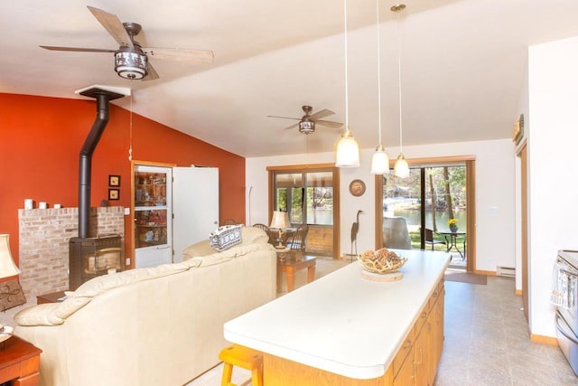 kitchen with a wood stove, open floor plan, ceiling fan, a baseboard heating unit, and vaulted ceiling