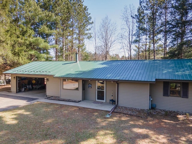 view of front of home with concrete driveway, metal roof, and an attached carport