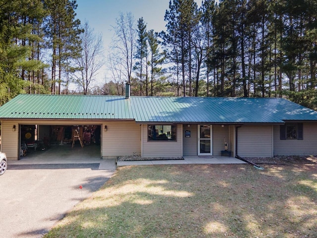 ranch-style home with a garage, a porch, metal roof, and aphalt driveway
