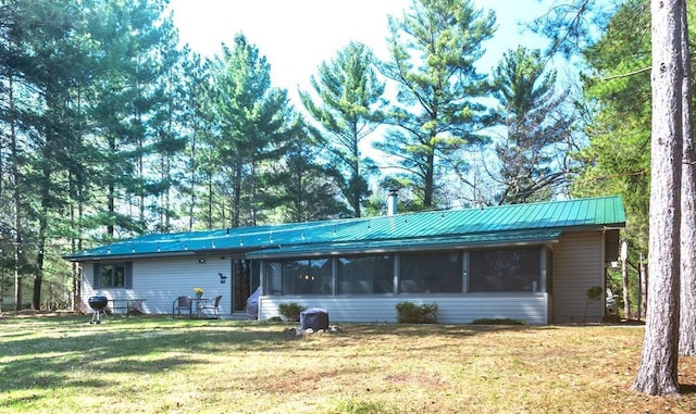 ranch-style house featuring a sunroom, metal roof, and a front yard