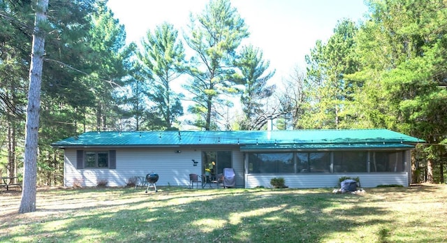 single story home featuring a sunroom, a front lawn, and metal roof
