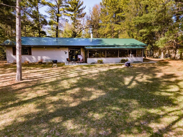 rear view of property with a lawn, a sunroom, and metal roof