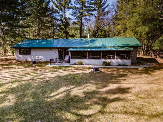 view of front of home featuring a patio, metal roof, a sunroom, and a front lawn