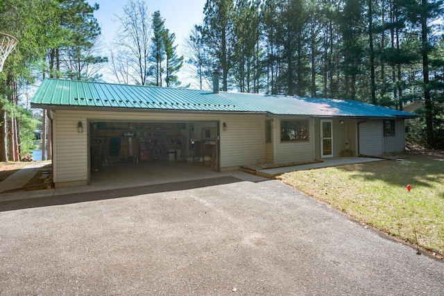 ranch-style house with a garage, a front lawn, driveway, and metal roof
