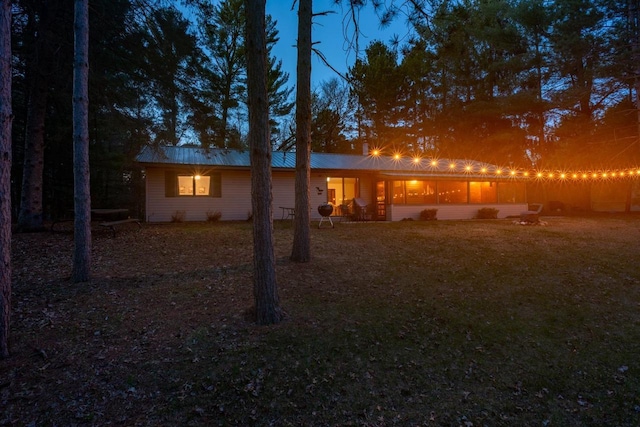 back of house at dusk featuring metal roof