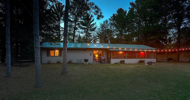rear view of house with a lawn and metal roof