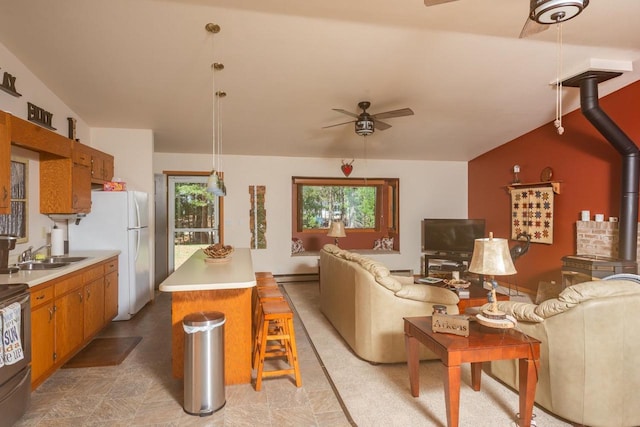 living area with baseboard heating, a wood stove, and a ceiling fan