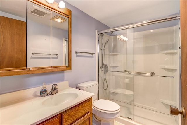 full bath featuring vanity, a stall shower, toilet, and visible vents