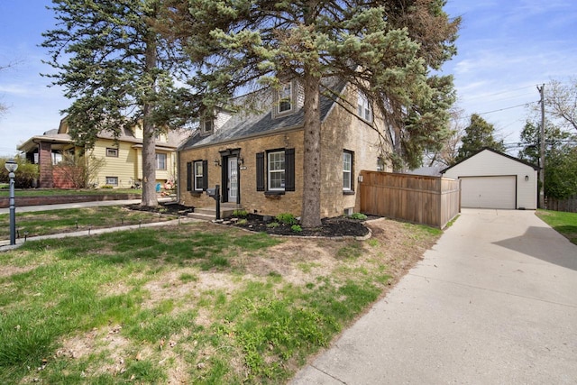 split level home featuring driveway, an outbuilding, a detached garage, brick siding, and fence