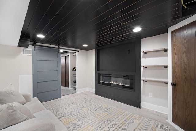 living room featuring a barn door, recessed lighting, baseboards, wood finished floors, and visible vents