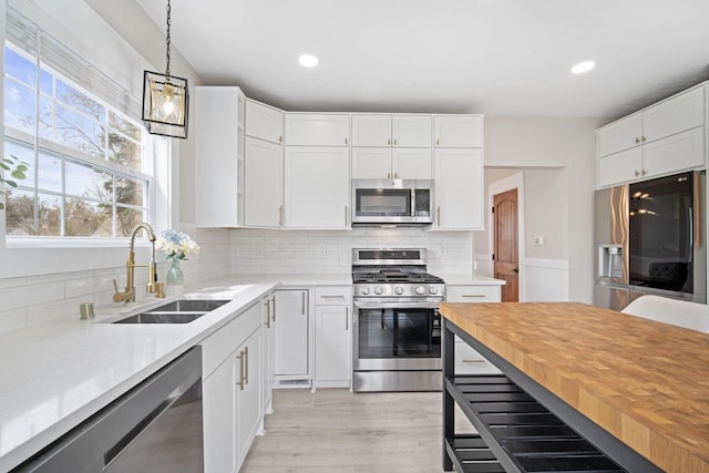 kitchen with a sink, white cabinets, appliances with stainless steel finishes, and a healthy amount of sunlight