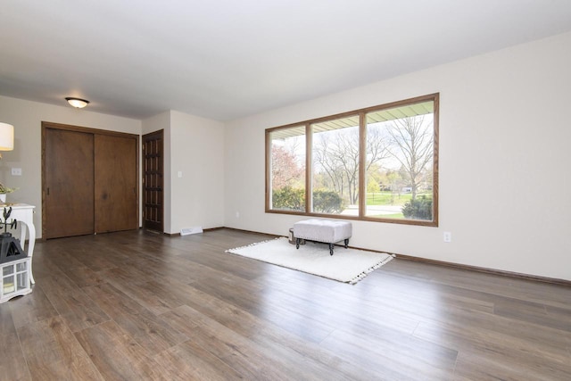 unfurnished living room featuring baseboards and dark wood finished floors