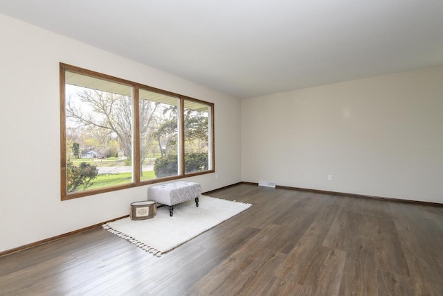 empty room featuring baseboards and dark wood-type flooring