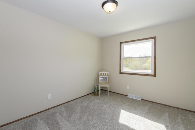 empty room featuring baseboards, visible vents, and light carpet