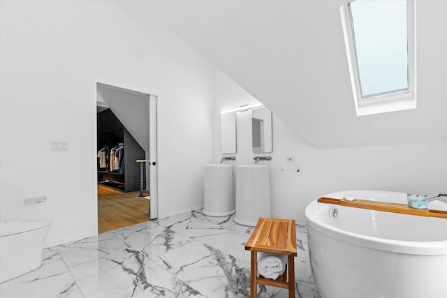 2627 N Farwell Ave, Milwaukee, WI 53211 - bathroom featuring a skylight, marble look tile flooring, a freestanding tub, toilet, and lofted ceiling