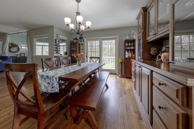 dining area featuring light wood-type flooring, plenty of natural light, and a chandelier