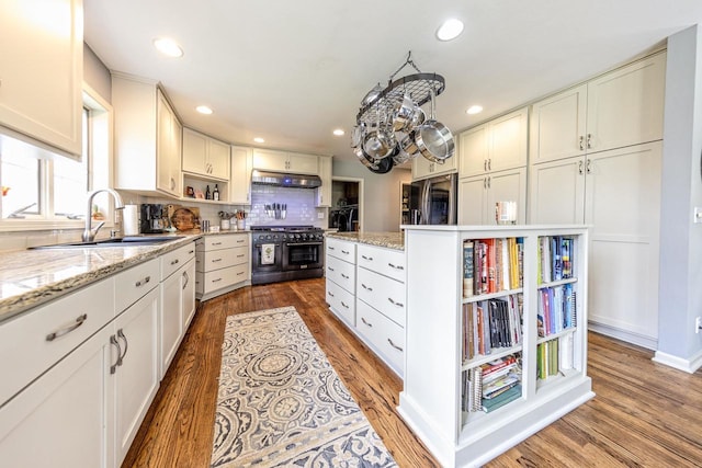 kitchen with a sink, open shelves, under cabinet range hood, and double oven range