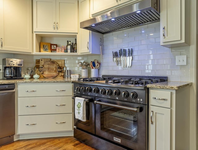 kitchen with light wood-style floors, decorative backsplash, under cabinet range hood, and range with gas cooktop