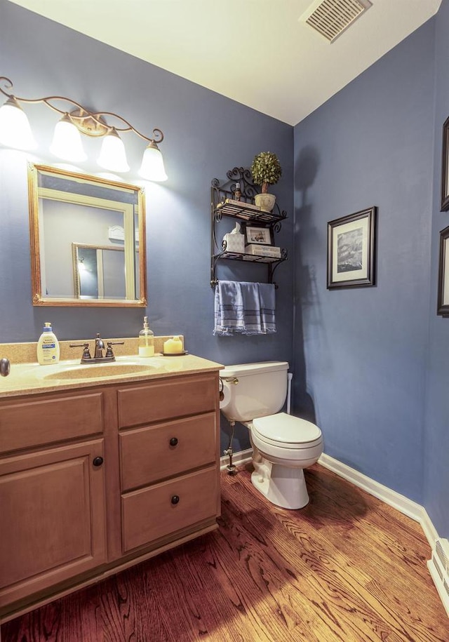 bathroom with visible vents, wood finished floors, baseboards, vanity, and toilet