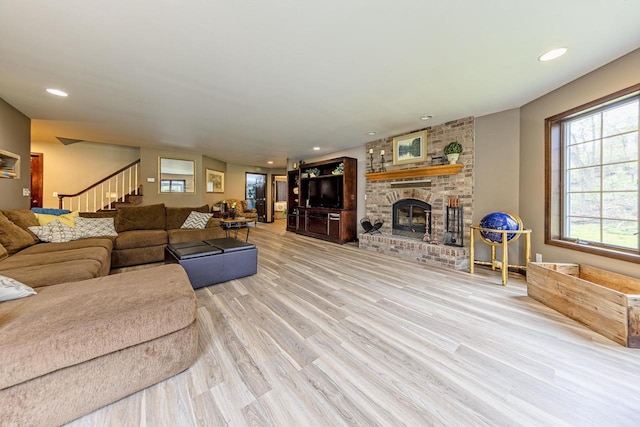 living room featuring recessed lighting, a brick fireplace, wood finished floors, and stairway