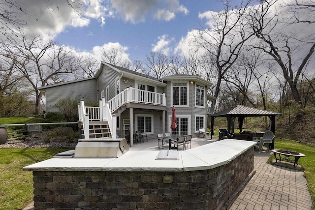 back of house with stairs, a gazebo, an outdoor fire pit, a wooden deck, and a patio