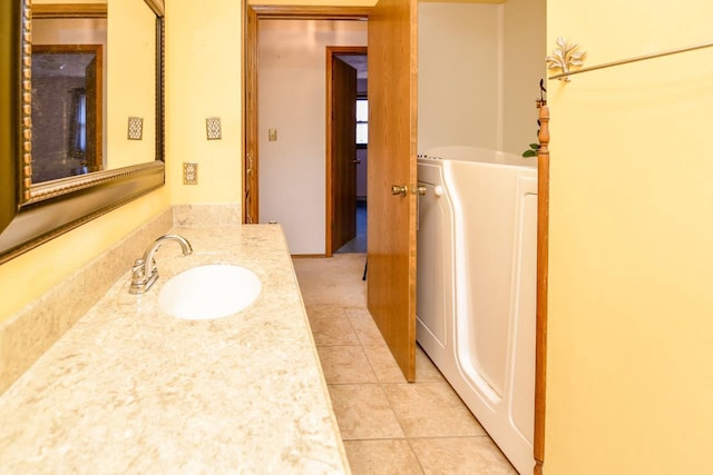bathroom with a bathing tub, tile patterned flooring, vanity, and washer / clothes dryer