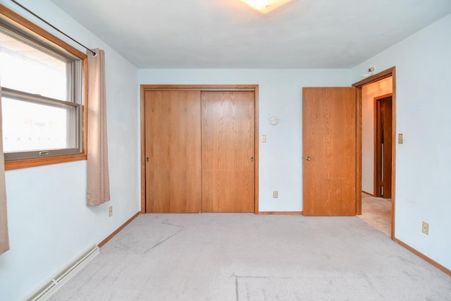 unfurnished bedroom with a closet, baseboards, light carpet, and a baseboard radiator