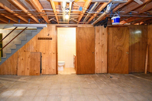 basement featuring wood walls and stairs