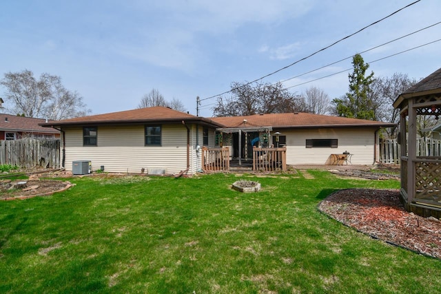 rear view of house with an outdoor fire pit, fence, a yard, and cooling unit