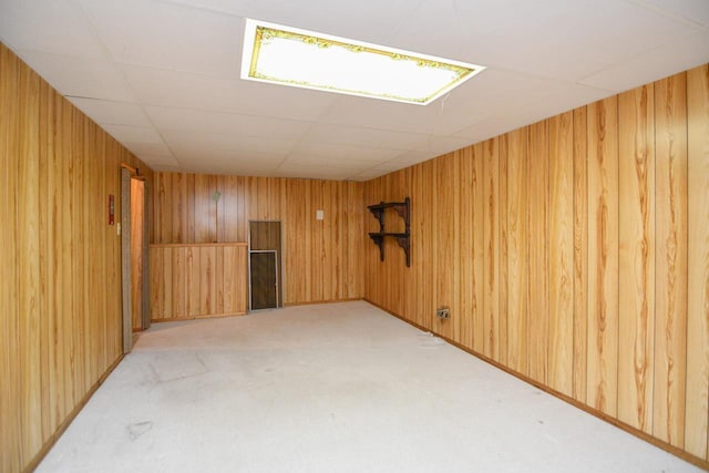 unfurnished room featuring wood walls and light carpet