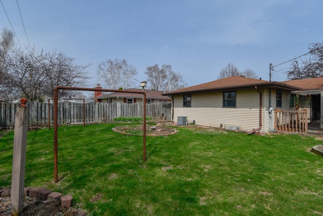 rear view of property with central air condition unit, a yard, and a fenced backyard