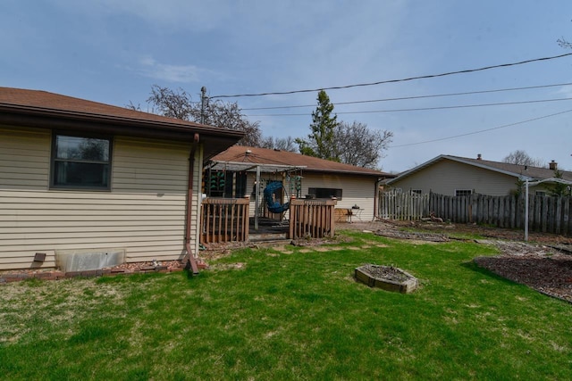rear view of house with fence, a yard, and a deck