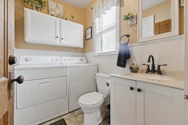 bathroom featuring washing machine and clothes dryer, toilet, vanity, and a wainscoted wall