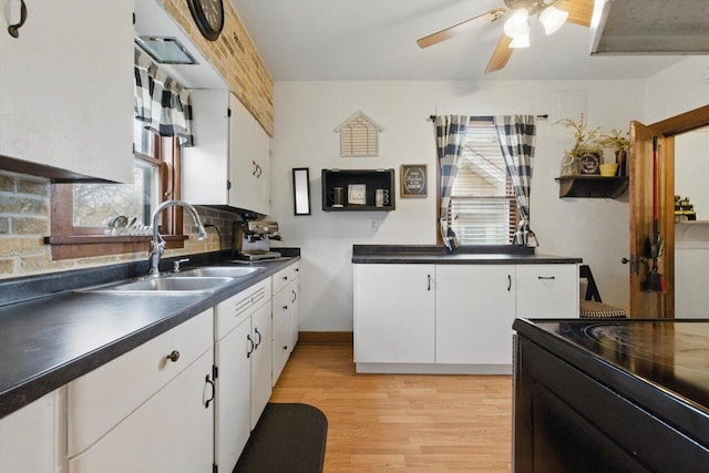 kitchen featuring a ceiling fan, dark countertops, light wood-type flooring, white cabinetry, and a sink