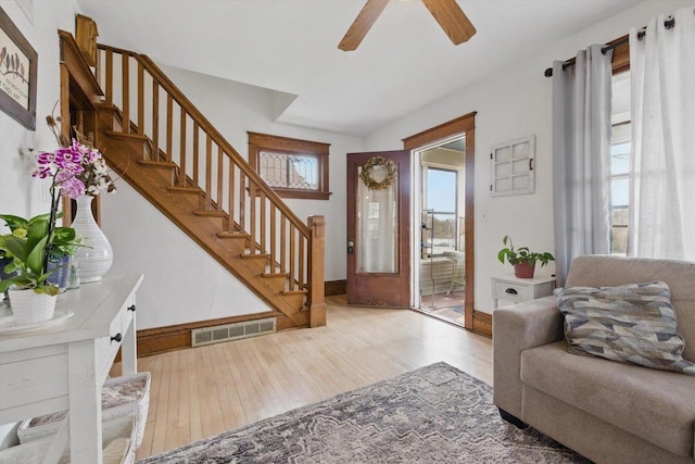 living room with stairs, a ceiling fan, baseboards, wood finished floors, and visible vents