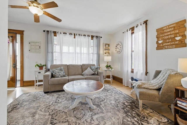 living area featuring baseboards, ceiling fan, and wood finished floors
