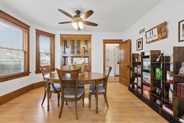dining space featuring baseboards, a ceiling fan, light wood-type flooring, and visible vents