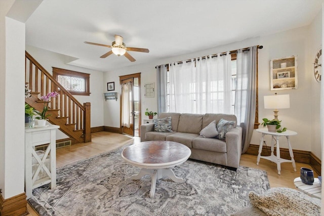 living room featuring baseboards, a ceiling fan, stairs, and wood finished floors