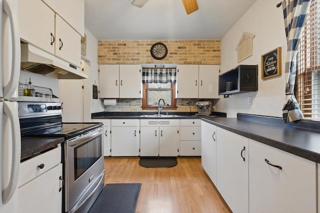 kitchen featuring a sink, under cabinet range hood, stainless steel electric stove, and dark countertops