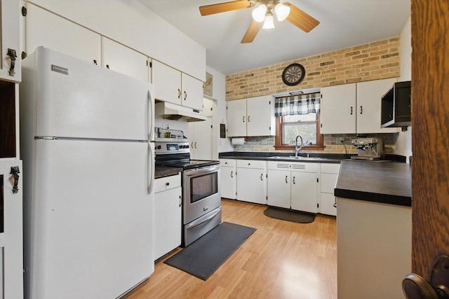 kitchen featuring dark countertops, a sink, white cabinets, under cabinet range hood, and stainless steel appliances