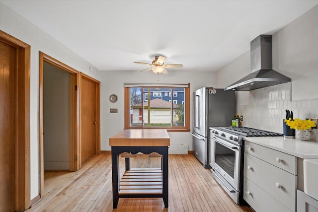 kitchen featuring ceiling fan, tasteful backsplash, extractor fan, stainless steel appliances, and light wood-style flooring